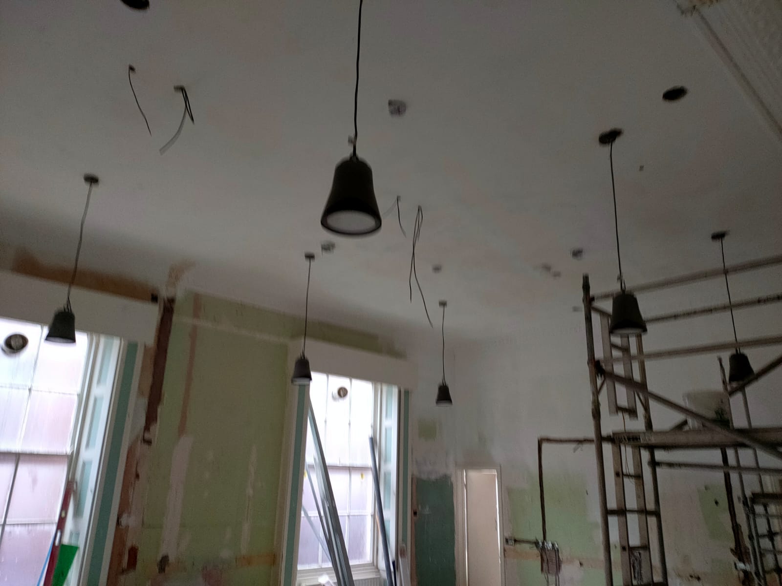 Multiple light fixtures dangling down with the wiring on the celling