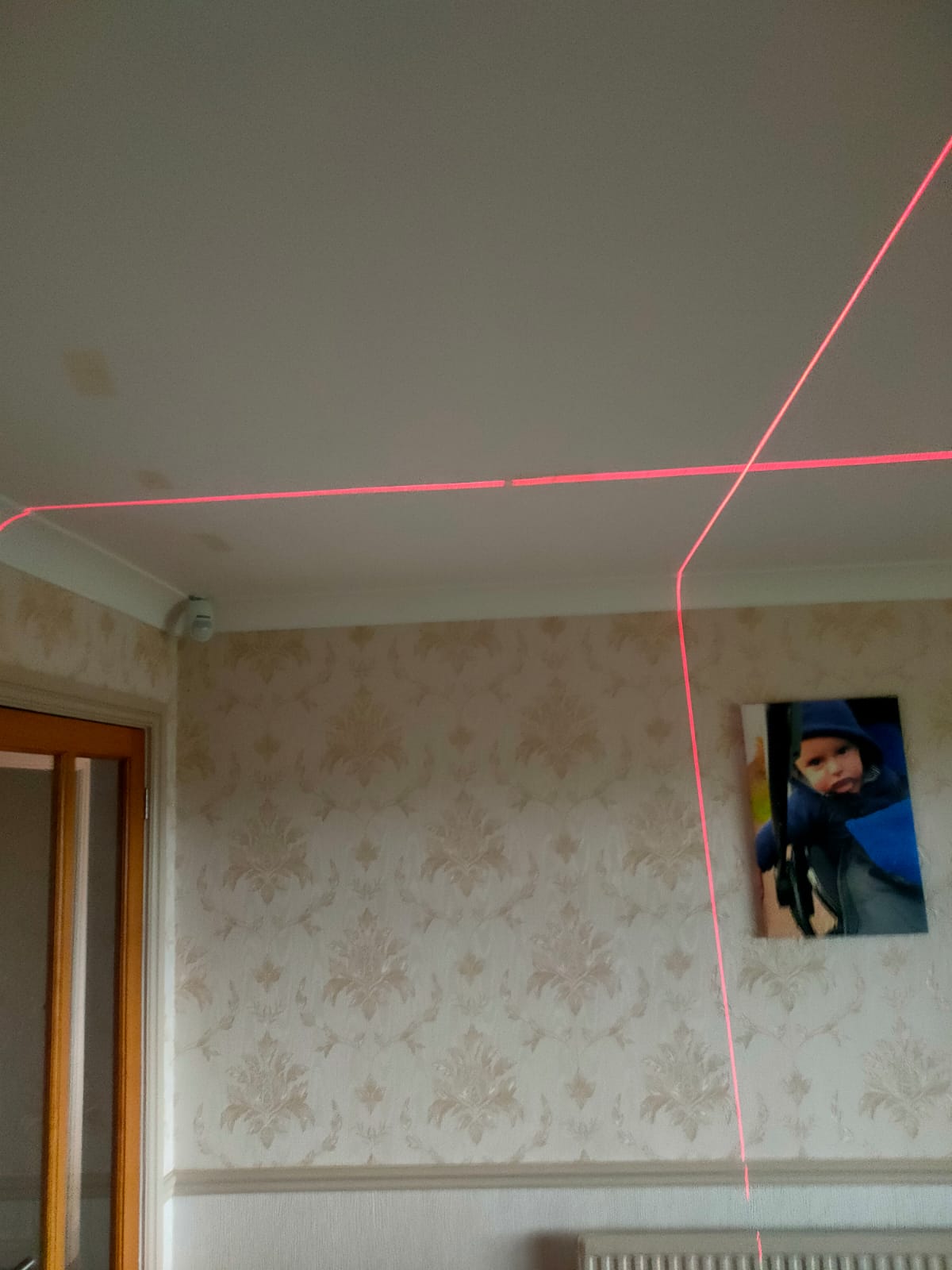 Using a laser level we can mark along the line using masking tape to show where each light will go, this is the laser level running across the celling in a perfect X