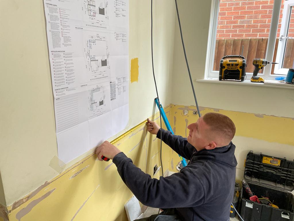 Alex rewiring a kitchen in Hilton, they are kneeled down working out the plan for some new socket positions